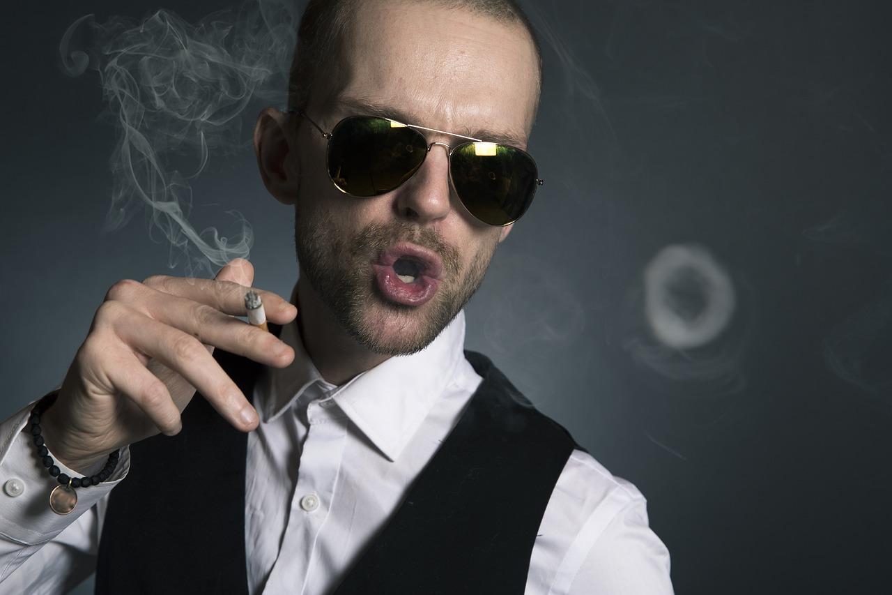 Man in shirt and sunglasses smoking and blowing a smoke ring