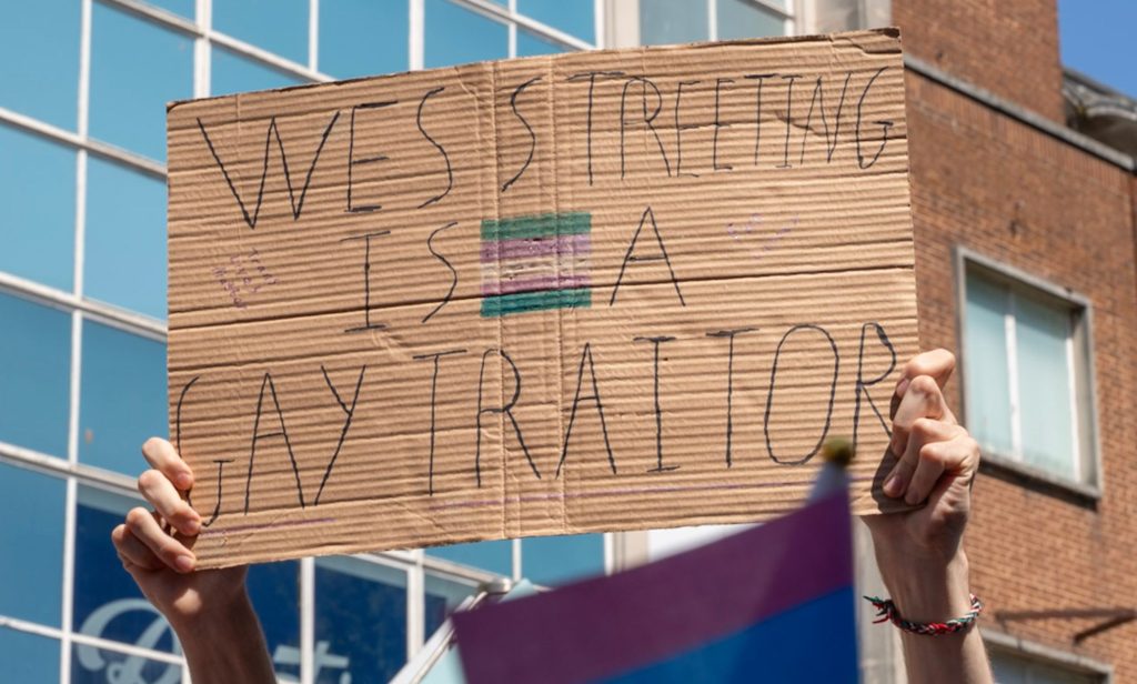 A protestor holds a sign that reads "Wes Streeting is a gay traitor."